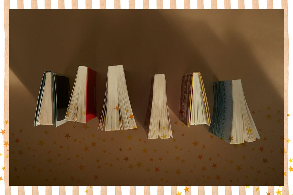 Five open books with star patterns on a brown background