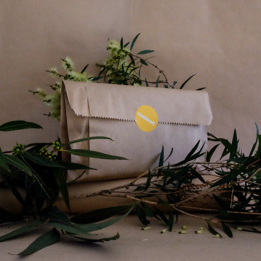Brown paper bag with a yellow label on a beige background with greenery